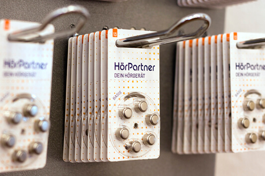 Hörgerätebatterien von HörPartner in Blisterverpackungen ordentlich im Regal präsentiert.